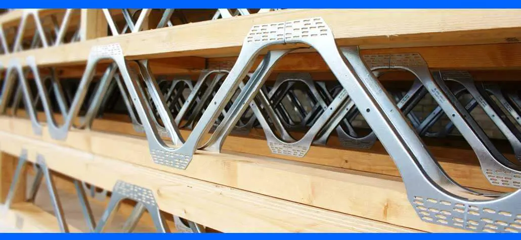 Metal truss brackets neatly stacked on wooden shelves, ready for construction use.