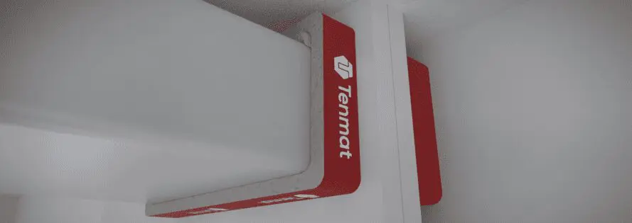 A red Tenmat firestop block installed around a steel beam in a white ceiling.