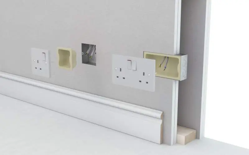 Three electrical outlet boxes being installed in a wall, with wires exposed and plates partially attached.