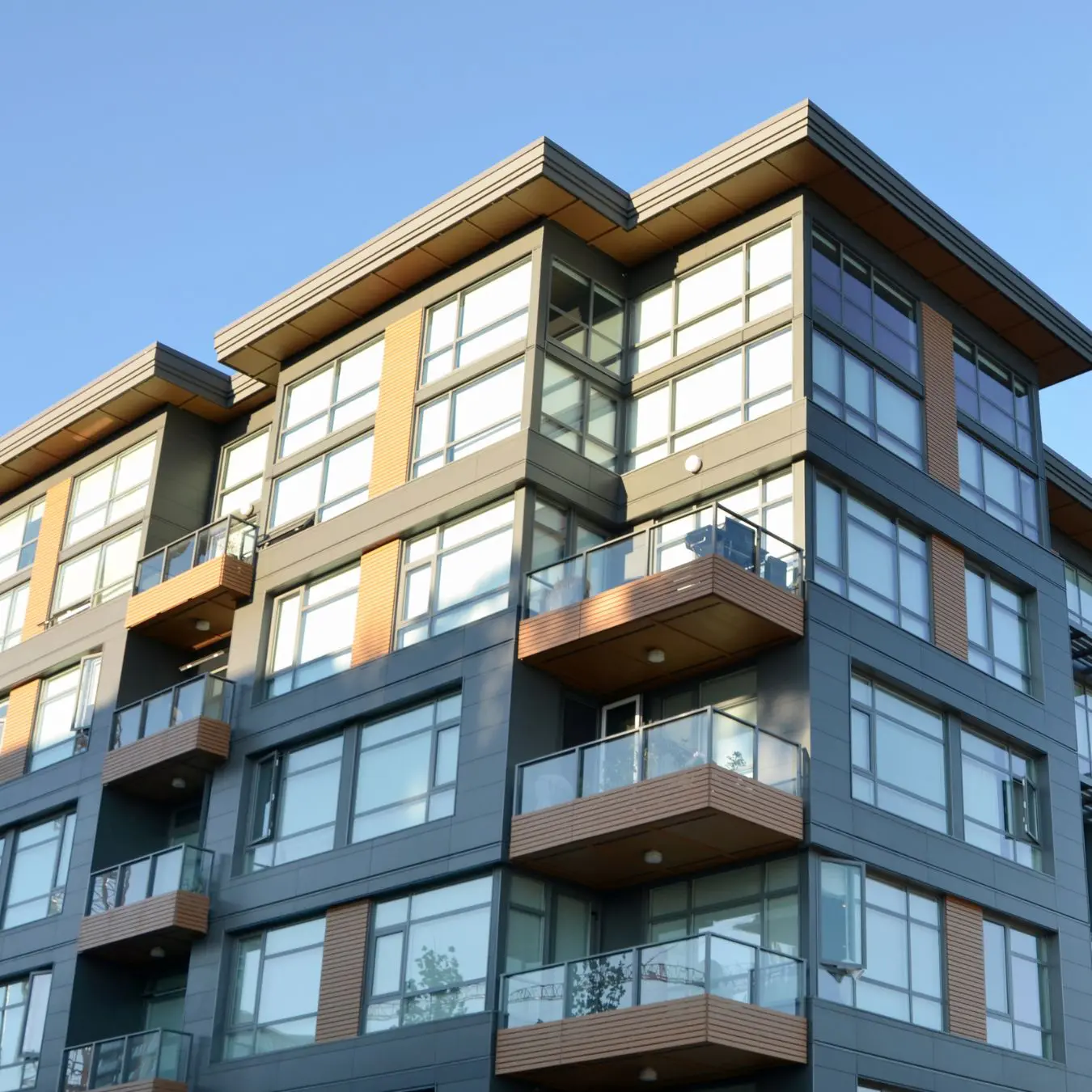 Modern apartment building with large windows and balconies against a clear blue sky.