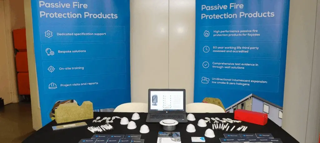 Exhibition table with fire protection products, brochures, and banners reading Passive Fire Protection Products.