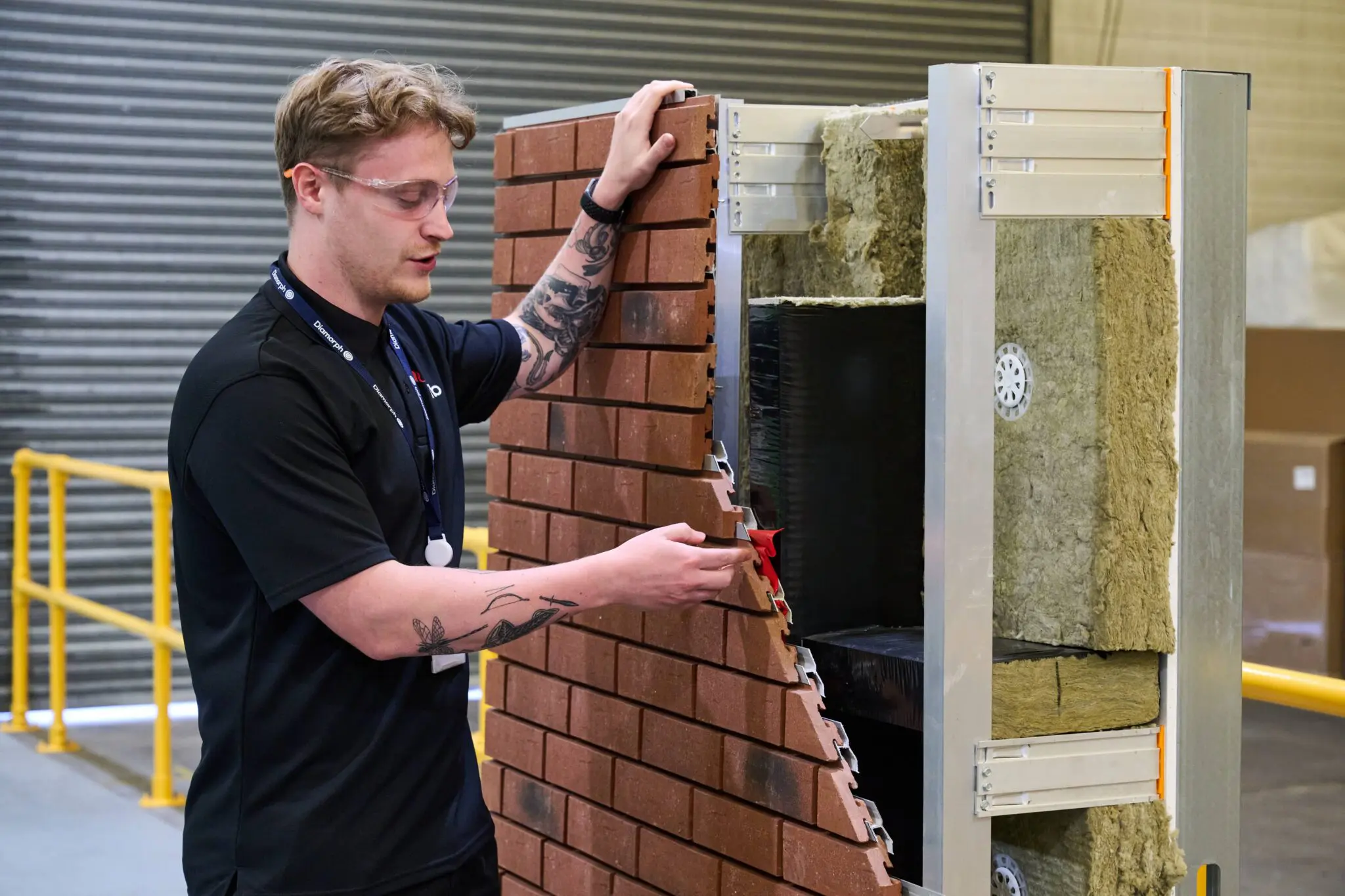 Man installs brick panel on insulated demonstration wall.