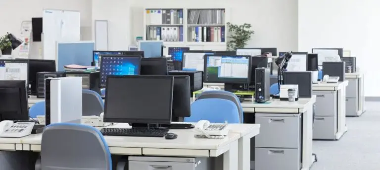 Open-plan office with empty desks, computers, and chairs.