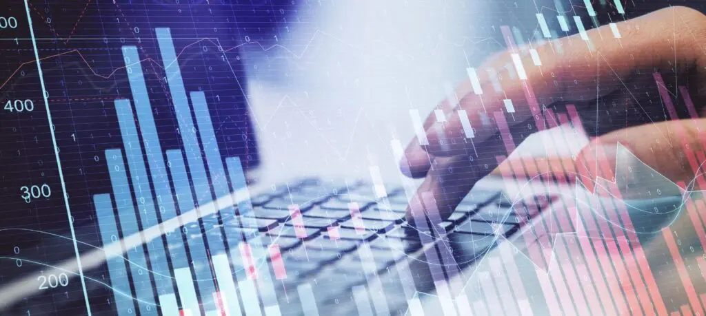 Hands typing on keyboard with financial graphs and charts overlaying the image.