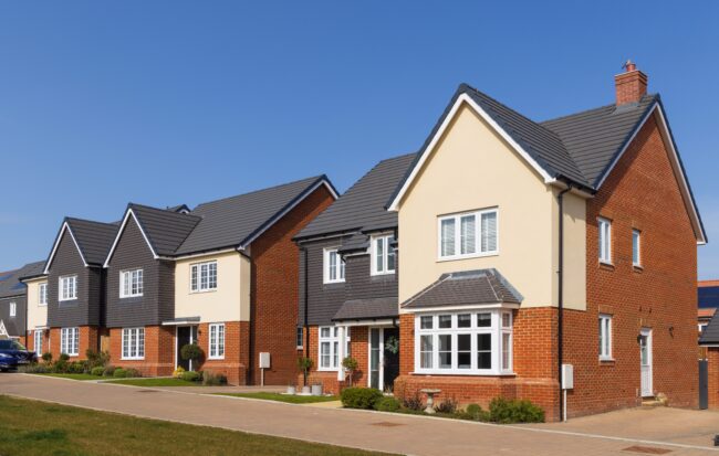 Bishop’s,Stortford.,Hertfordshire.,Uk.,March,22nd,2022.,Row,Of,Detached Row of modern detached suburban houses with brick and cream exteriors, under a clear blue sky.