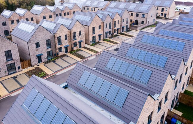 Aerial view of modern houses with solar panels on their roofs in a residential neighborhood.