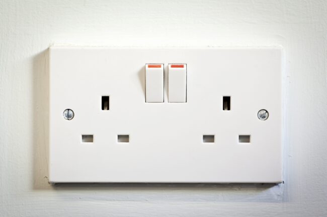 A white electrical outlet with two switches and two sockets on a white wall.
