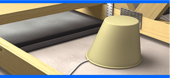 A beige plastic cup covering a white cable on a floor framed by wooden beams and metal brackets.