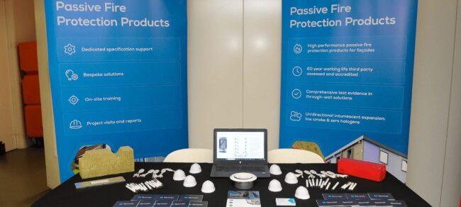 Exhibition table with fire protection products, brochures, and banners reading Passive Fire Protection Products.