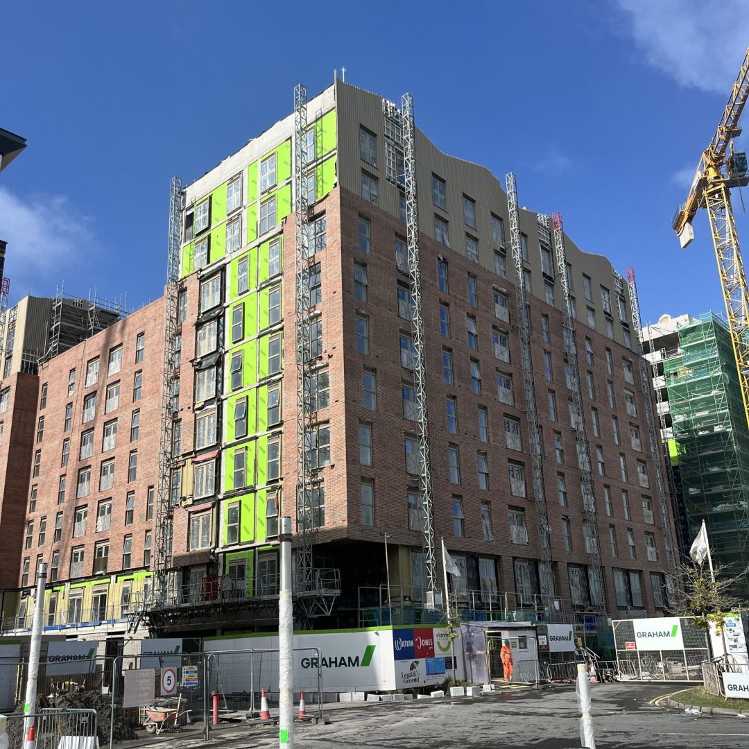 Building under construction, green insulation panels and scaffolding visible.