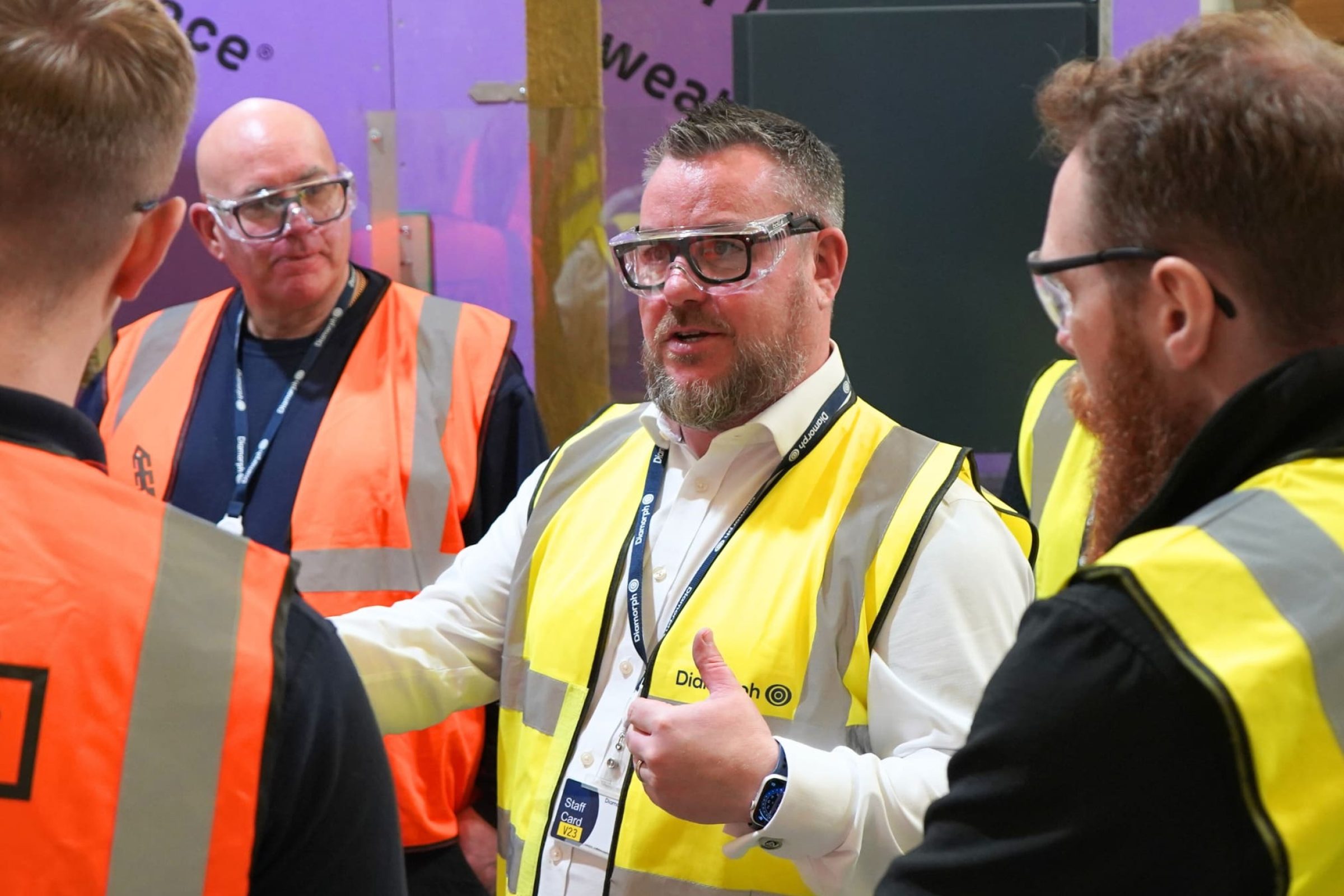 Men in safety vests talk about fire protection at a construction training site.